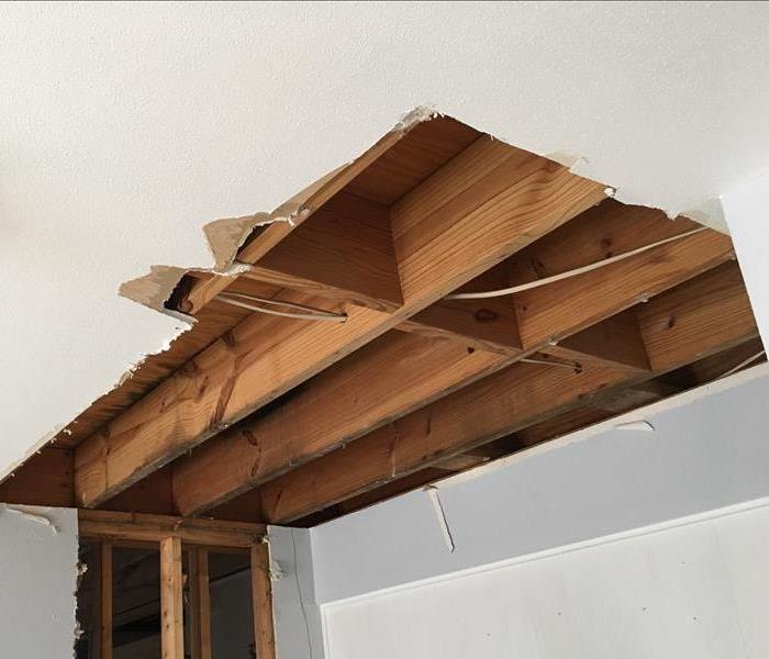 Affected ceiling drywall removed and the underlying wood framework is showing