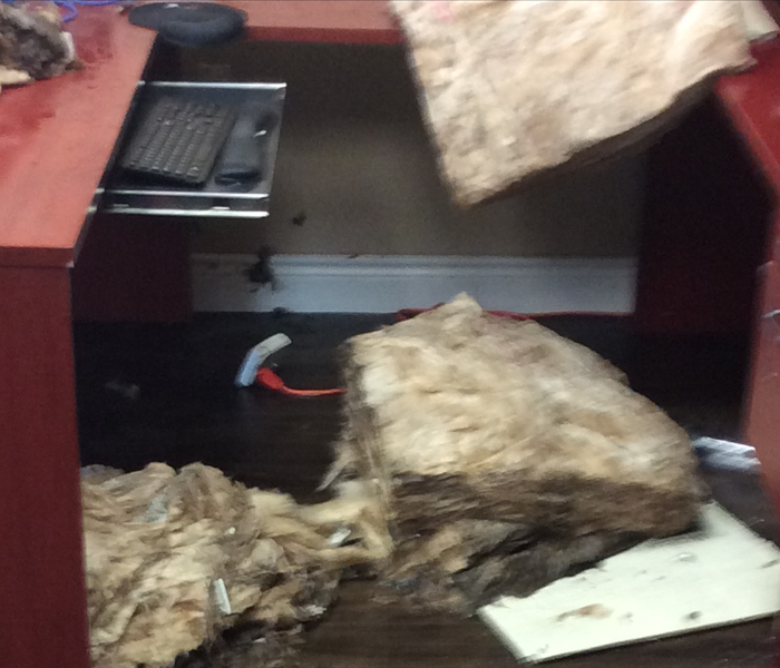 Saturated insulation that fell from a ceiling onto a red desk