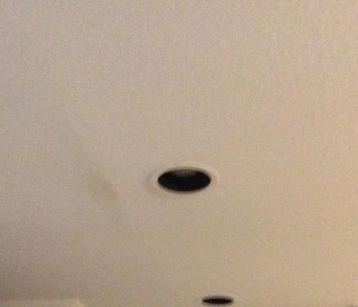Beige ceiling with water damage stain next to a light fixture