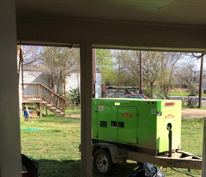 Green SERVPRO generator in a backyard